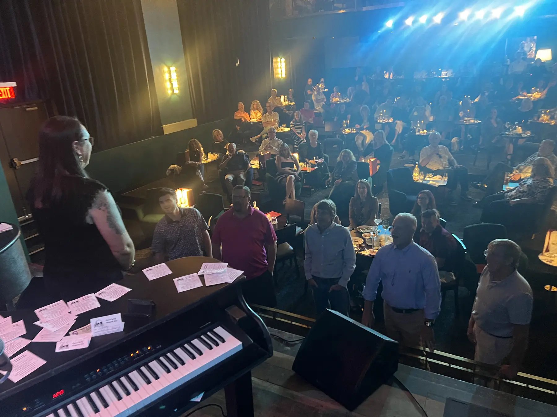 Adult audience members gathered near the pianos during a live show