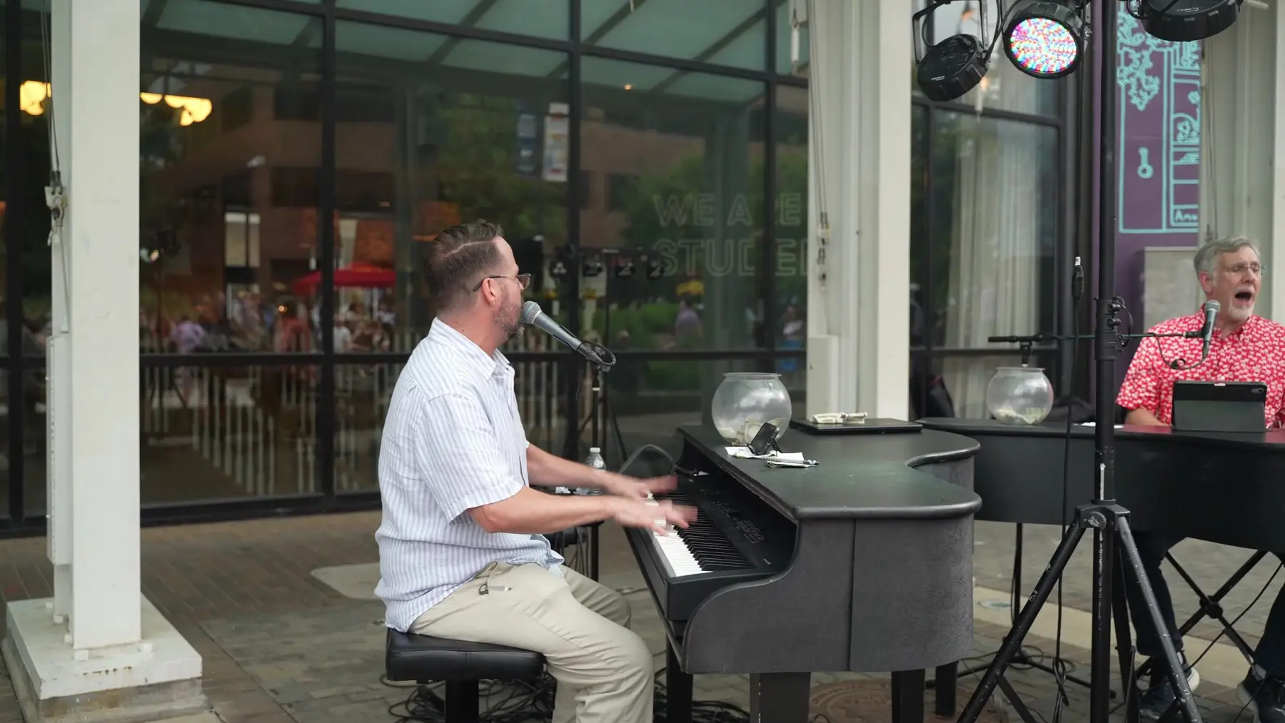 Elijah Hubbard at the piano with a second performer during an outdoor show