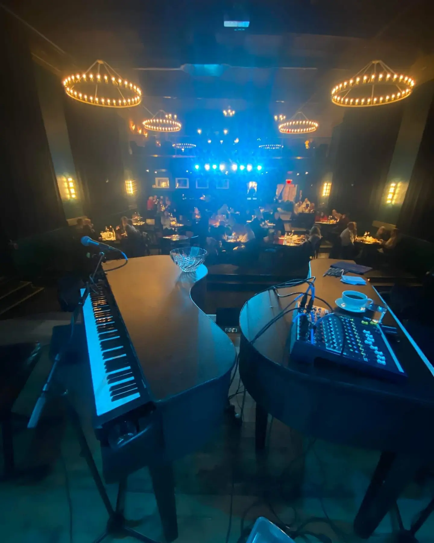 View from two pianos toward adult guests in a warmly lit venue