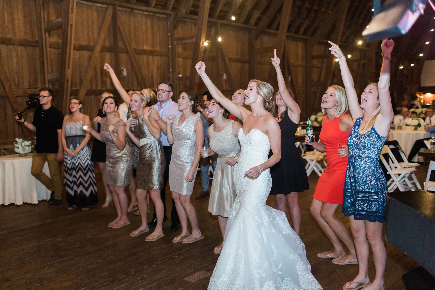 Bride and adult wedding guests singing and cheering on a dance floor